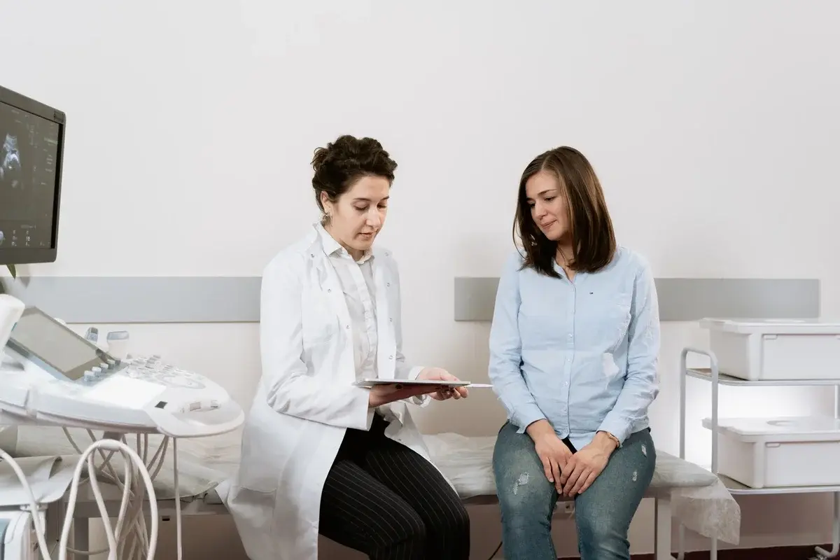 A pregnant woman speaking with a gynecologist in a clinic.