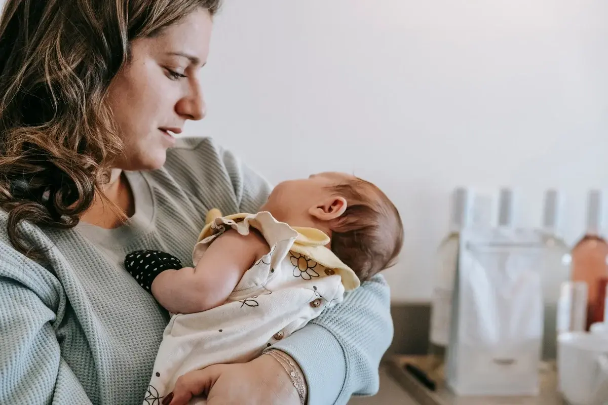A mother holding her newborn baby in a bright home interior.