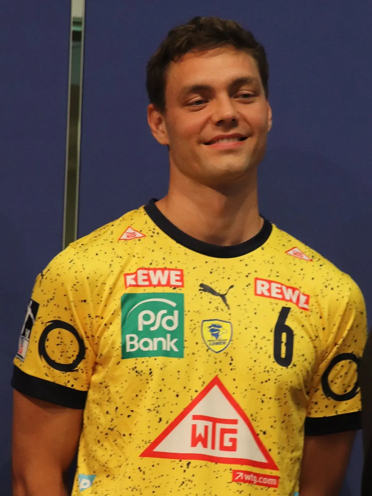 A man in a yellow Löwen jersey posing for a photo.