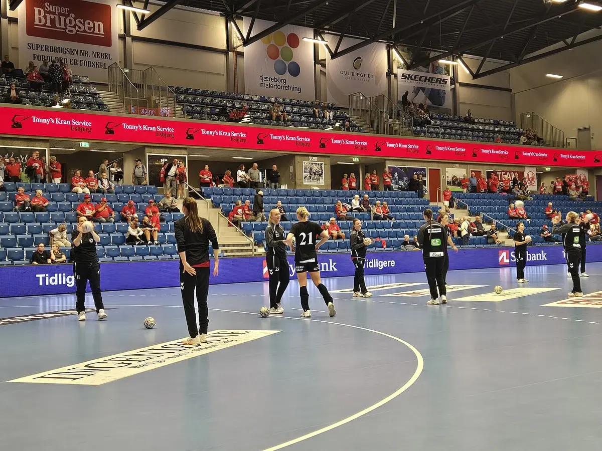 Team Esbjerg players warm up on an indoor handball court.