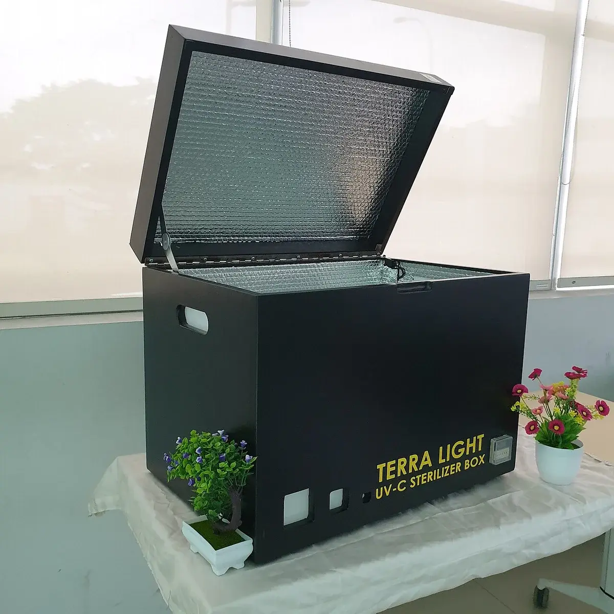 An open black UV-C sterilizer box on a table indoors.
